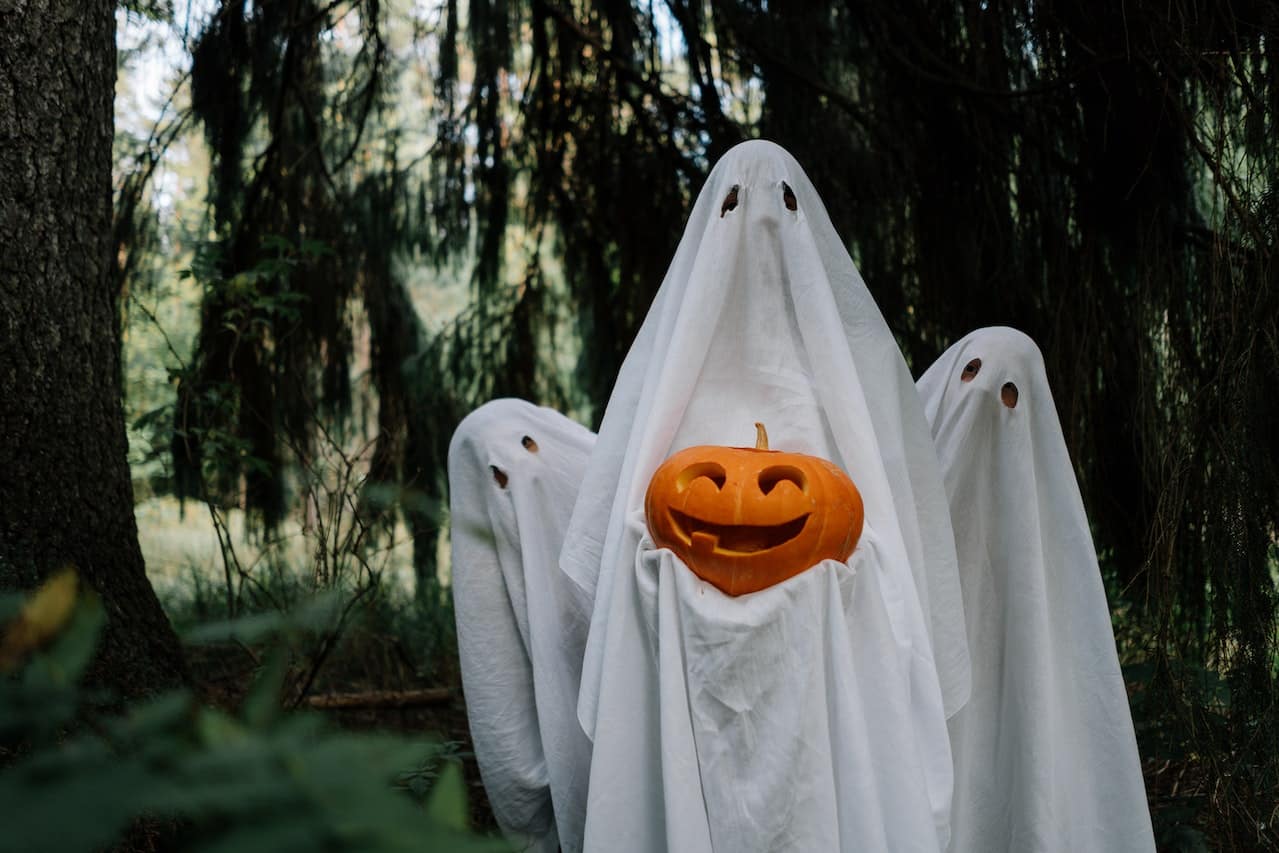 Three ghosts holding a pumpkin