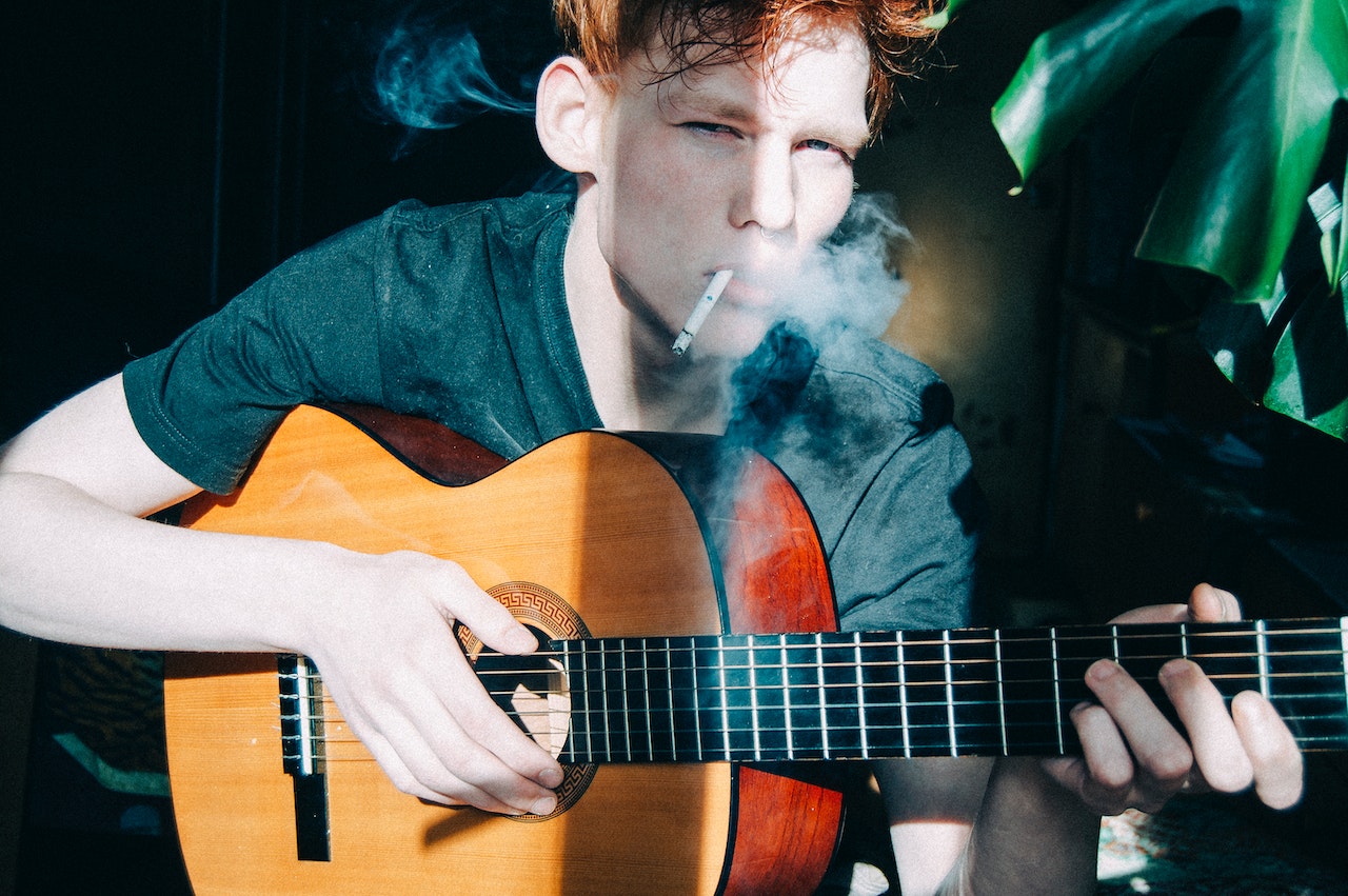 Boy playing guitar and smoking